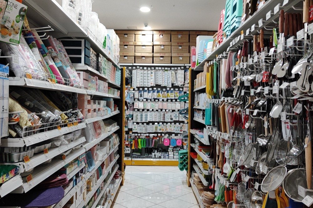 Une allée de quincaillerie-bazar, rayonnages remplis d'ustensiles et d'articles de maison