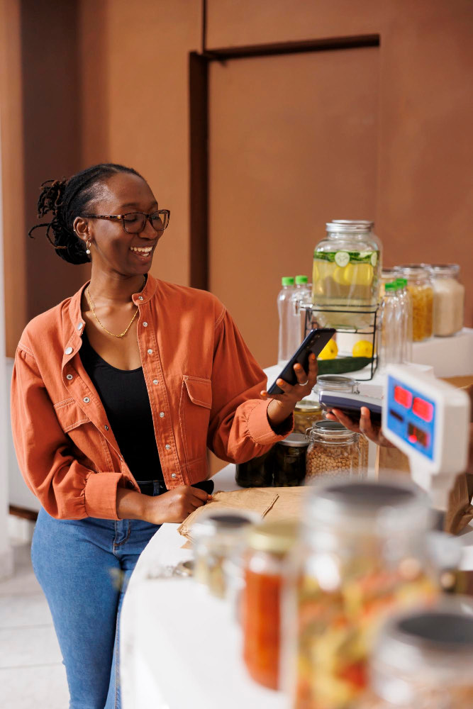 Une commerçante, téléphone en main, derrière son comptoir garni de bocaux et d'une balance